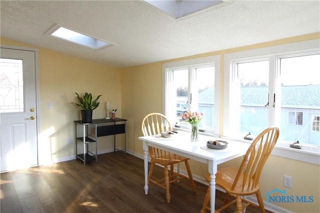 dining room featuring dark wood-type flooring, a textured ceiling, and a skylight