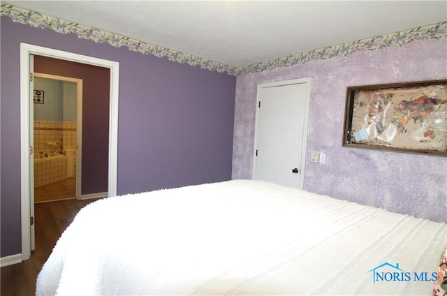 bedroom with dark wood-type flooring and connected bathroom