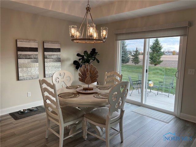 dining area featuring wood-type flooring and an inviting chandelier