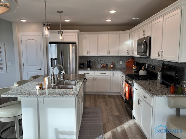 kitchen featuring white cabinetry, stainless steel appliances, sink, and a breakfast bar area