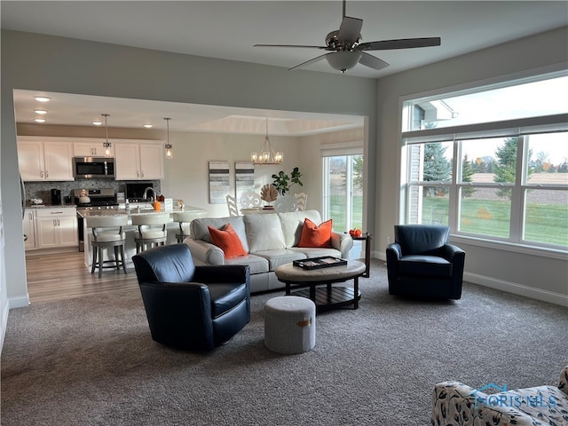 living room with ceiling fan with notable chandelier and carpet