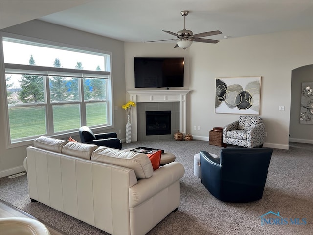 carpeted living room featuring ceiling fan and a tile fireplace