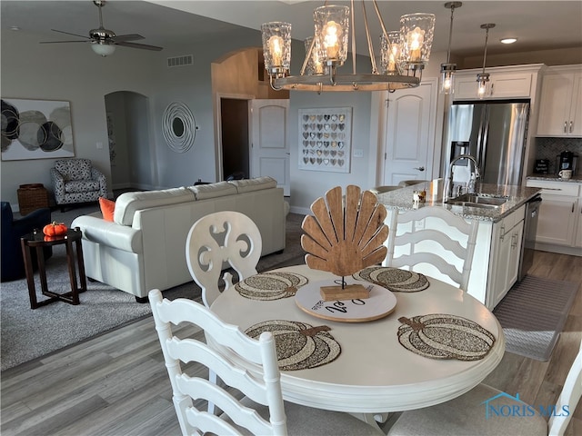 dining room featuring light hardwood / wood-style floors, ceiling fan with notable chandelier, and sink