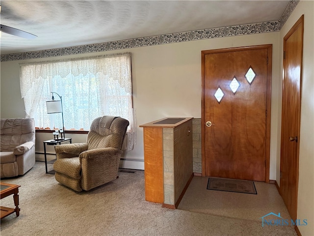 foyer entrance with a textured ceiling, ceiling fan, light carpet, and a baseboard heating unit