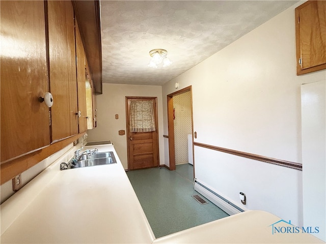 clothes washing area with a textured ceiling, sink, and a baseboard heating unit