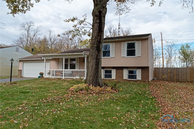 tri-level home with covered porch, a garage, and a front lawn