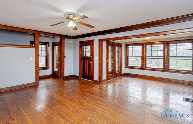 unfurnished room with ornate columns, ceiling fan, hardwood / wood-style floors, a textured ceiling, and ornamental molding