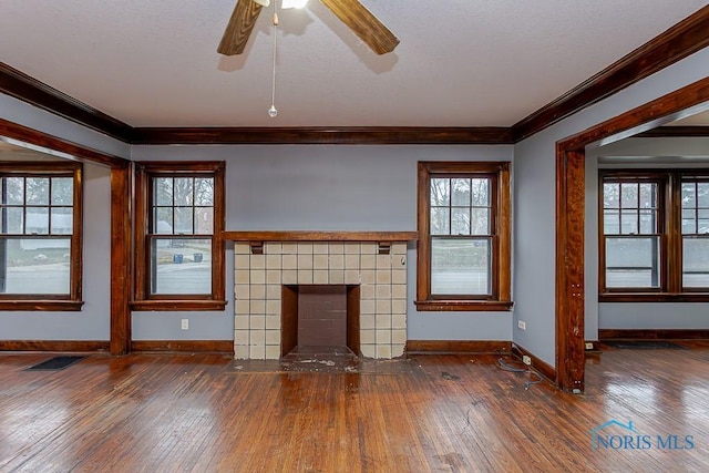 unfurnished living room with a tile fireplace, dark wood-type flooring, and ornamental molding