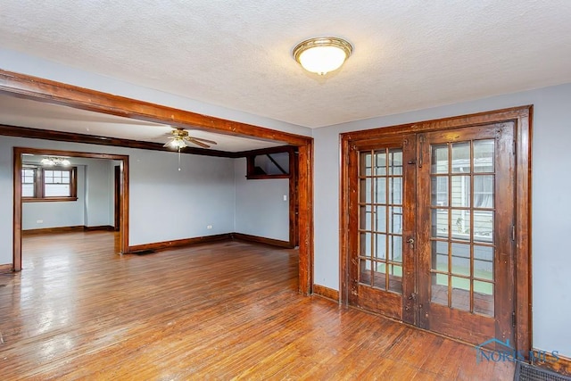 empty room with hardwood / wood-style floors, french doors, a textured ceiling, and ceiling fan