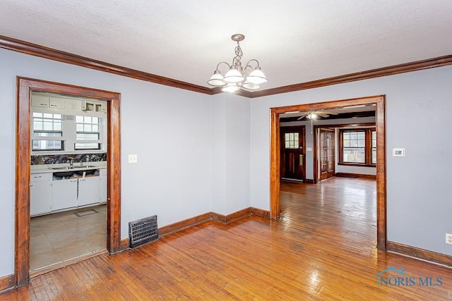 unfurnished room with a textured ceiling, hardwood / wood-style flooring, and crown molding