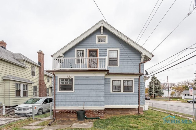 rear view of property featuring a yard and a balcony