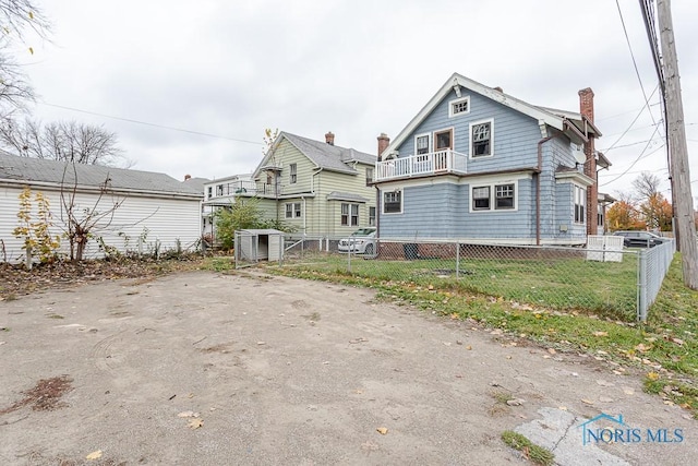 back of house with a balcony and a lawn