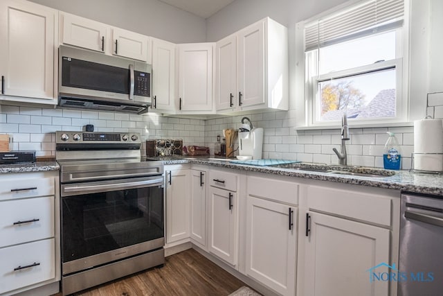 kitchen with tasteful backsplash, appliances with stainless steel finishes, dark hardwood / wood-style floors, sink, and white cabinets