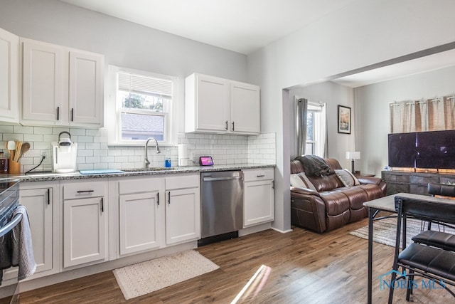 kitchen featuring hardwood / wood-style flooring, white cabinetry, sink, tasteful backsplash, and stainless steel dishwasher