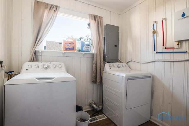 laundry area featuring dark hardwood / wood-style floors, electric panel, washing machine and dryer, water heater, and wooden walls