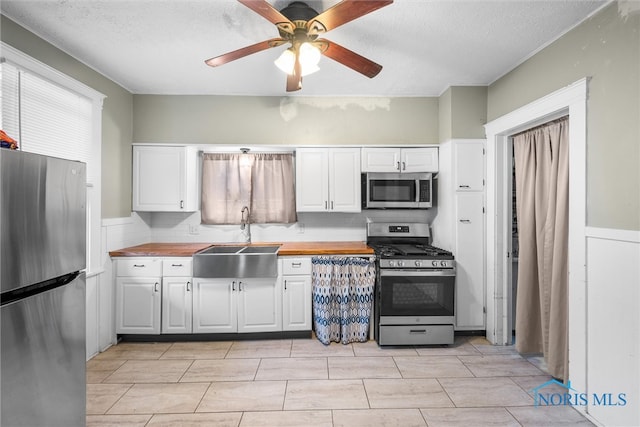 kitchen with butcher block counters, white cabinetry, appliances with stainless steel finishes, and sink