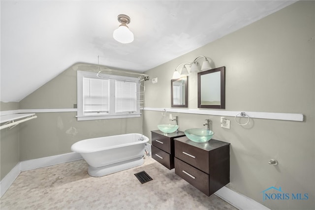 bathroom with a tub to relax in, vanity, and vaulted ceiling