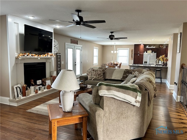 living room with a textured ceiling, ceiling fan, and dark wood-type flooring