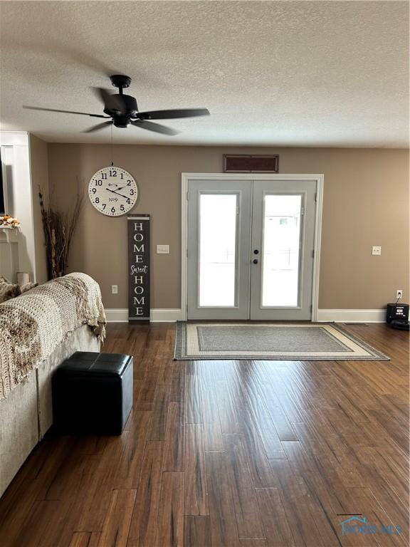 unfurnished bedroom with ceiling fan, a textured ceiling, dark hardwood / wood-style flooring, and french doors