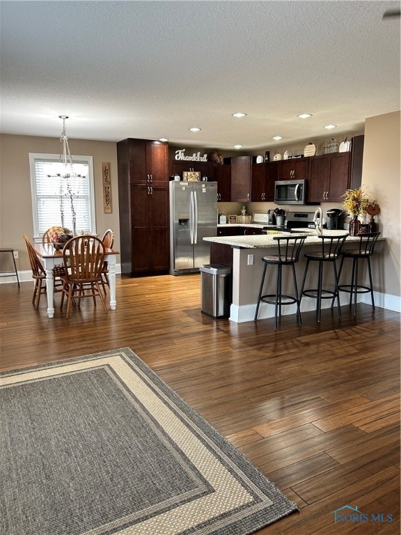 kitchen with hanging light fixtures, dark hardwood / wood-style flooring, a breakfast bar, and stainless steel appliances