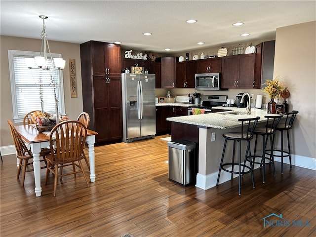 kitchen featuring appliances with stainless steel finishes, sink, decorative light fixtures, light hardwood / wood-style flooring, and a notable chandelier