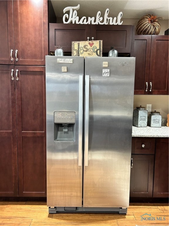 kitchen featuring light hardwood / wood-style floors, light stone countertops, and stainless steel fridge with ice dispenser