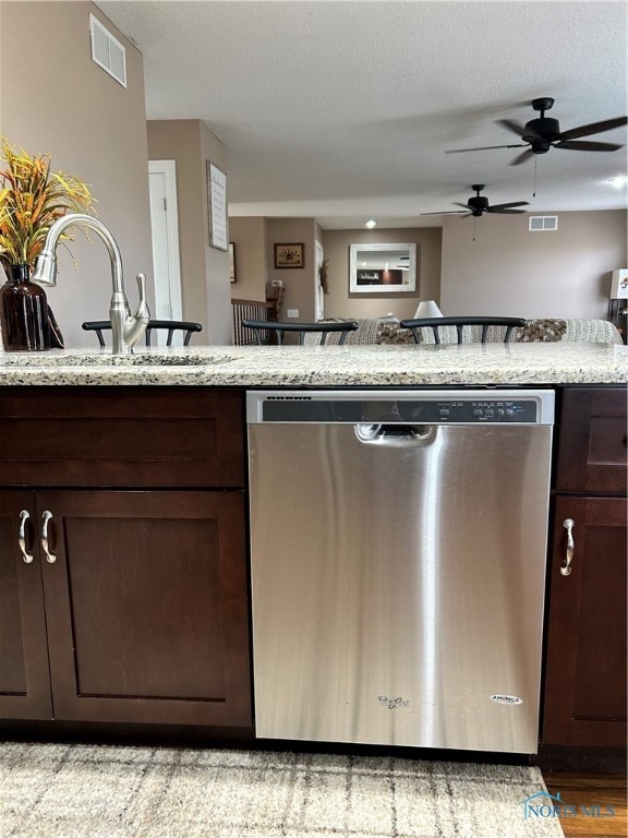 kitchen with dishwasher, sink, a textured ceiling, dark brown cabinets, and light hardwood / wood-style floors