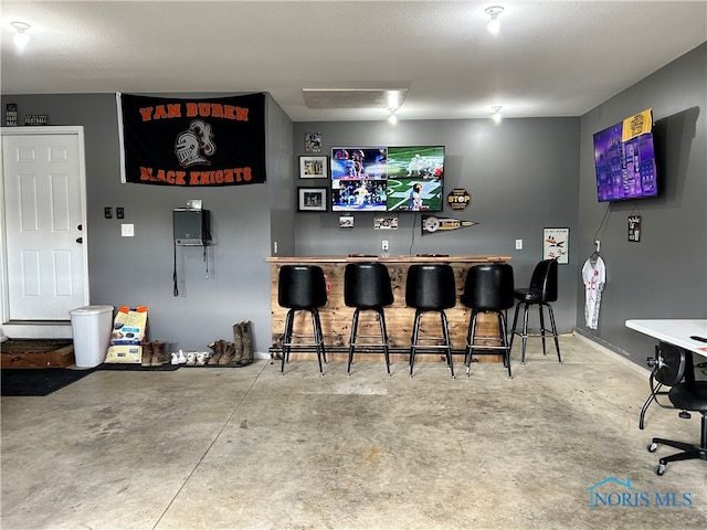 bar featuring concrete floors and a textured ceiling