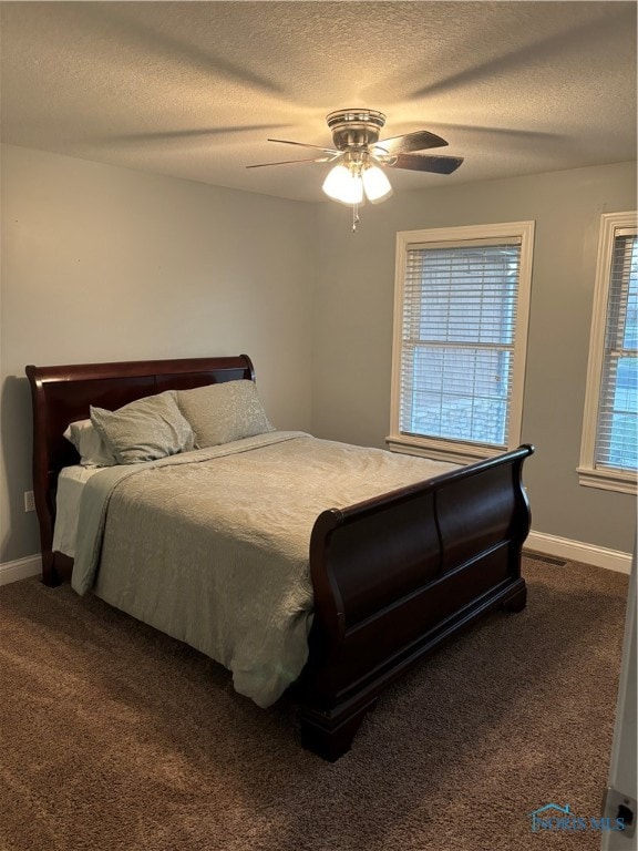 carpeted bedroom with multiple windows, a textured ceiling, and ceiling fan