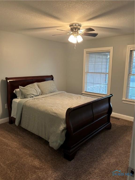 bedroom with ceiling fan, carpet, and a textured ceiling