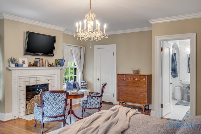 bedroom with hardwood / wood-style flooring, ensuite bath, ornamental molding, a fireplace, and a chandelier