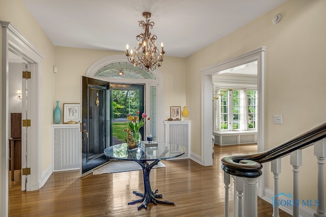 foyer with a wealth of natural light, an inviting chandelier, and dark hardwood / wood-style floors