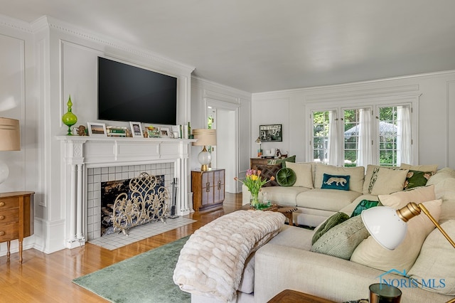 living room featuring wood-type flooring and a tiled fireplace