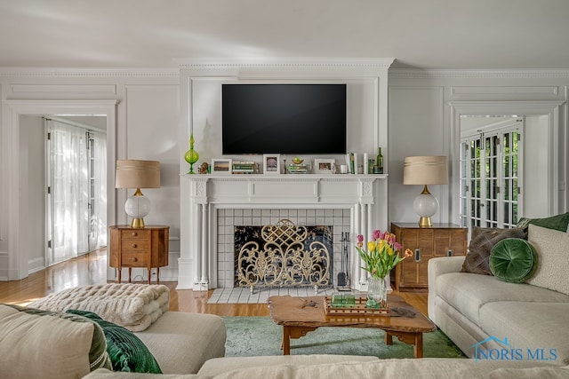 living room with ornamental molding, hardwood / wood-style floors, and a tile fireplace