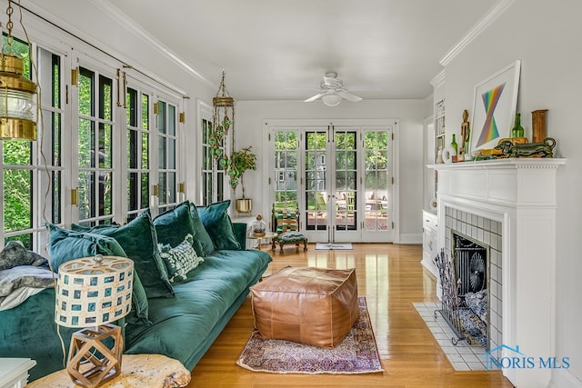 sunroom / solarium featuring a wealth of natural light, french doors, ceiling fan, and a fireplace