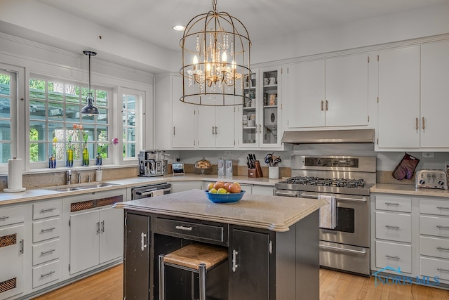 kitchen with stainless steel appliances, light wood-type flooring, white cabinetry, decorative light fixtures, and a center island