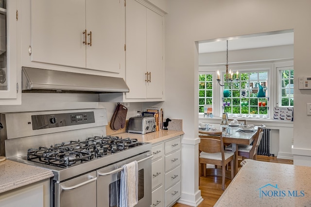 kitchen featuring decorative light fixtures, light wood-type flooring, stainless steel gas range, and white cabinets