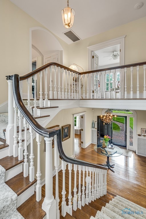 stairway with hardwood / wood-style flooring and a chandelier