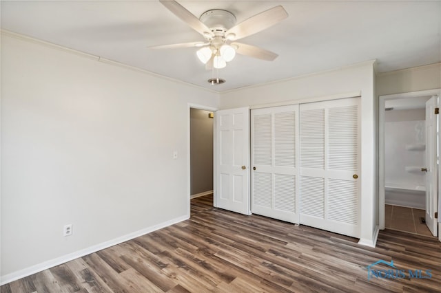 unfurnished bedroom with ornamental molding, dark wood-type flooring, ceiling fan, and a closet