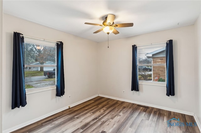 empty room featuring dark wood-type flooring, ceiling fan, and a healthy amount of sunlight