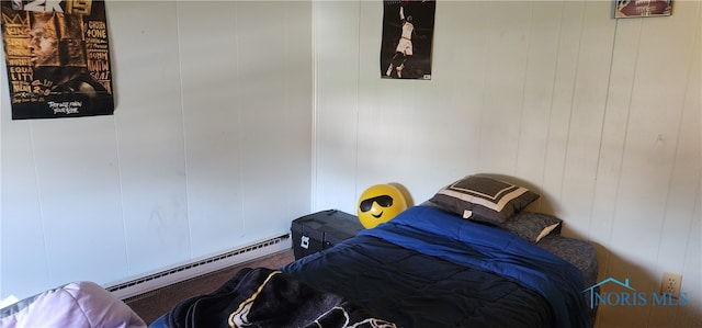 bedroom with wooden walls and a baseboard heating unit