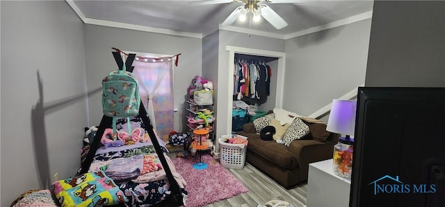 bedroom featuring ornamental molding, a closet, light wood-type flooring, and ceiling fan