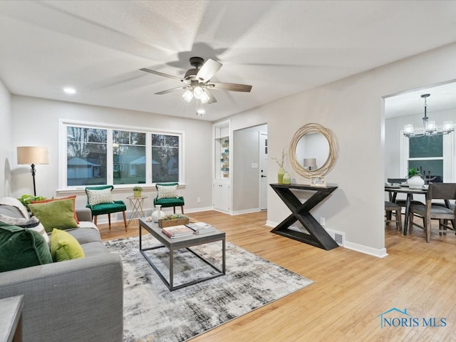 living room featuring ceiling fan with notable chandelier and hardwood / wood-style flooring