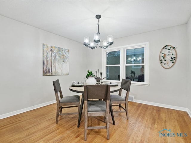 dining space with a chandelier and light wood-type flooring