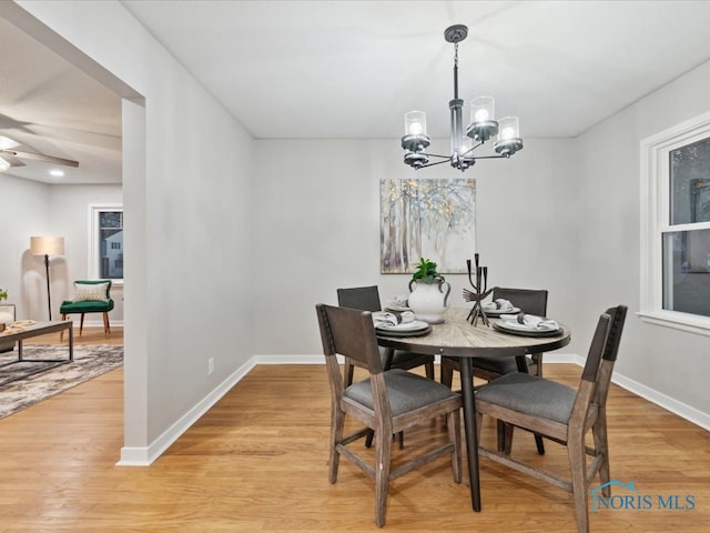 dining area with light wood-type flooring and ceiling fan with notable chandelier