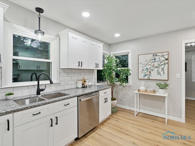 kitchen featuring light stone counters, white cabinets, sink, stainless steel dishwasher, and light wood-type flooring