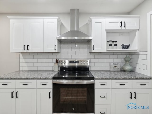 kitchen with electric stove, backsplash, wall chimney range hood, light stone countertops, and white cabinets