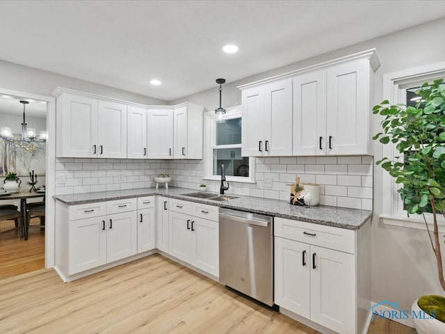 kitchen with white cabinetry, tasteful backsplash, light wood-type flooring, stainless steel dishwasher, and pendant lighting