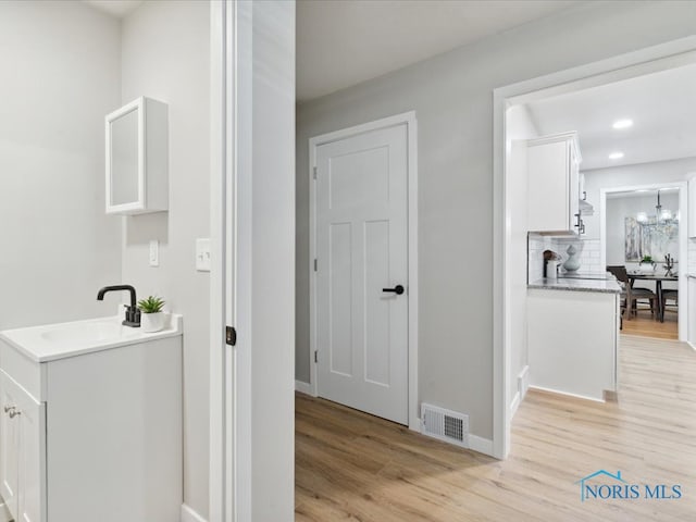 bathroom with a chandelier, wood-type flooring, sink, and tasteful backsplash