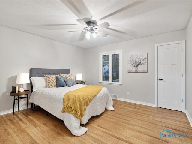 bedroom with a textured ceiling, hardwood / wood-style flooring, and ceiling fan